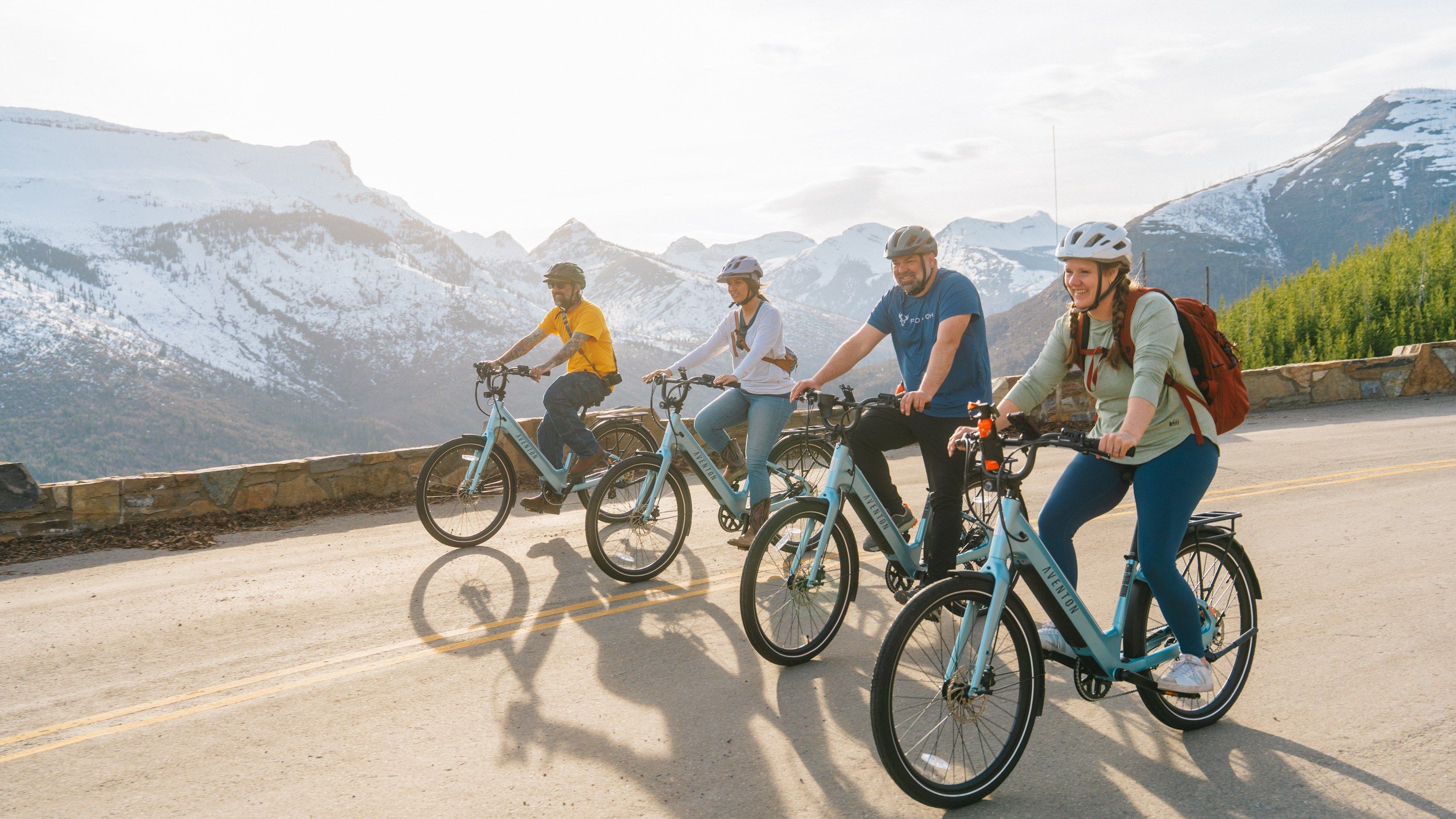 Riders on e-bikes on a paved trail with the mountains of the Flathead Valley behind