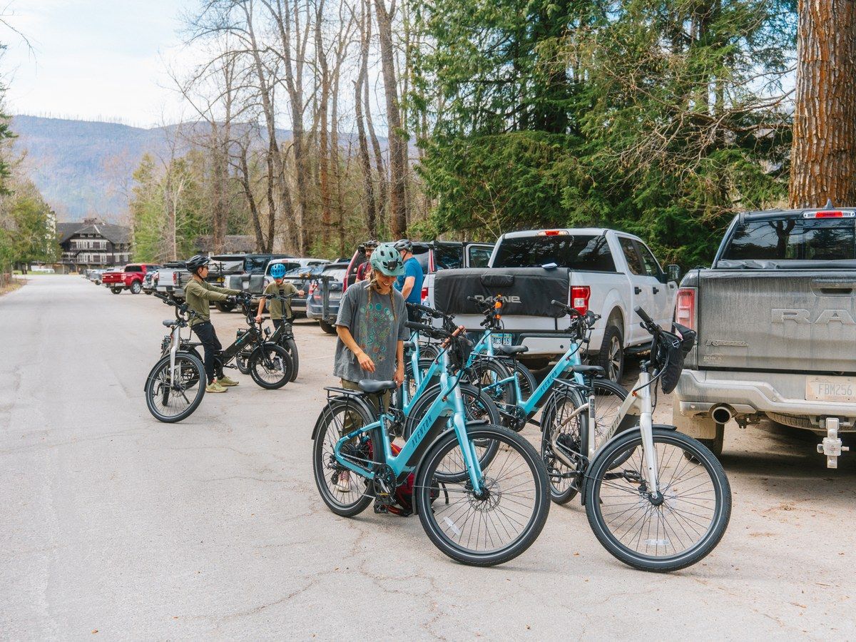 E-bikes on a hitch rack behind a truck at a trailhead