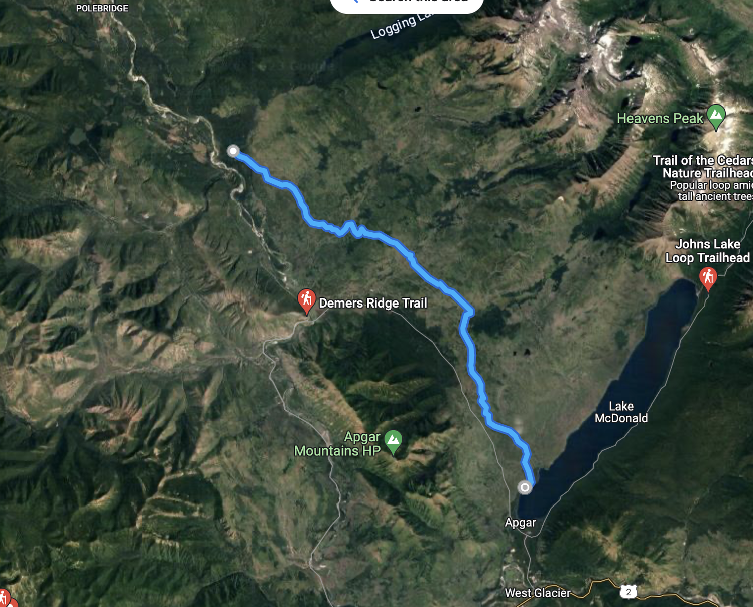 Satellite map showing the Apgar region in Glacier National Park, highlighting trails and geographical features such as Lake McDonald and Demers Ridge Trail. A blue route is marked, connecting Polebridge to Apgar. Nearby locations include Logging Mountain, Trap of the Cedars, and Heavens Peak.